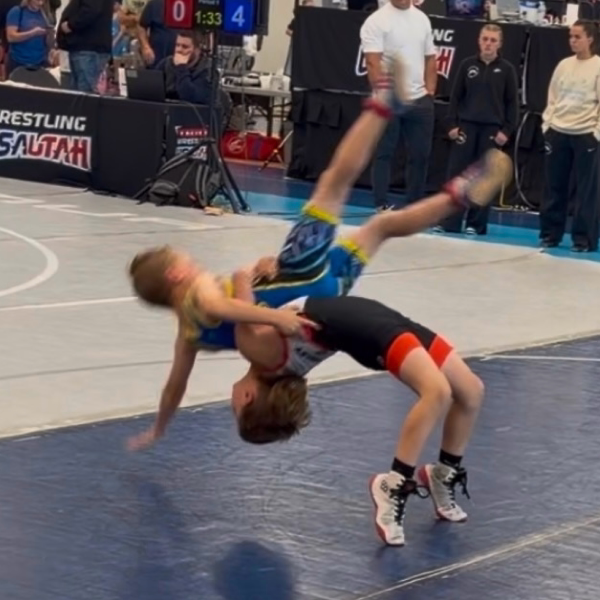 Young wrestler lifting and throwing an opponent during a freestyle match