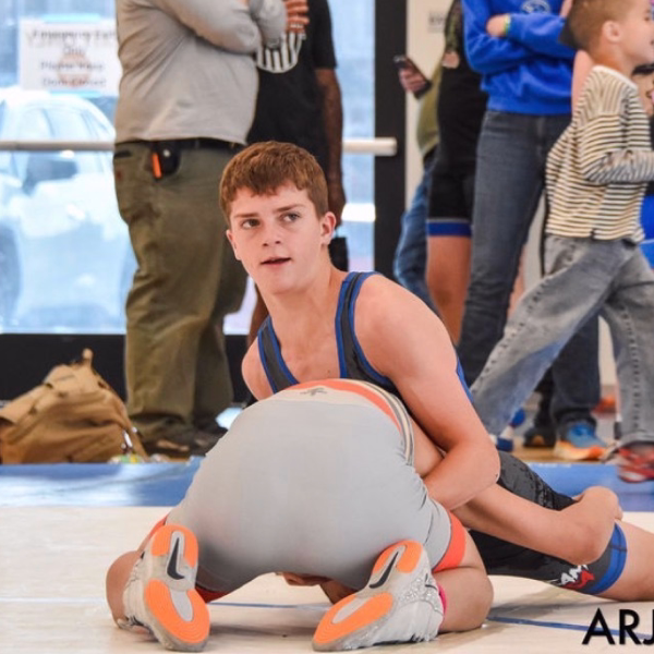 Junior high wrestler in control on top of an opponent during a match